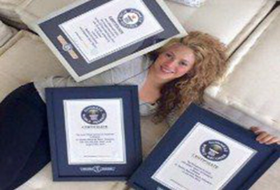 Shakira beams with pride as she lays on the couch with her newly-framed Guinness World Record triumphs